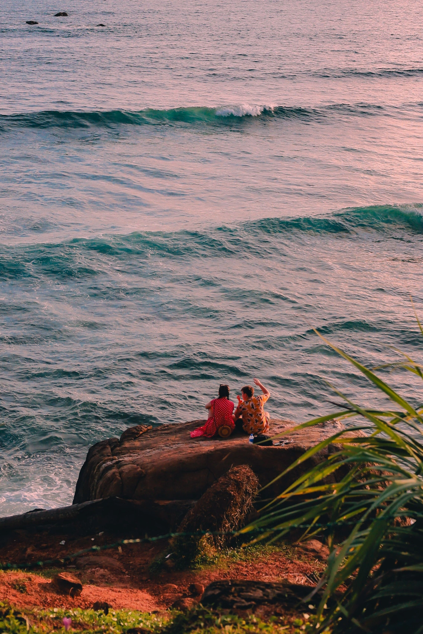 Couple sitting together on coastal rocks at sunset in Sri Lanka